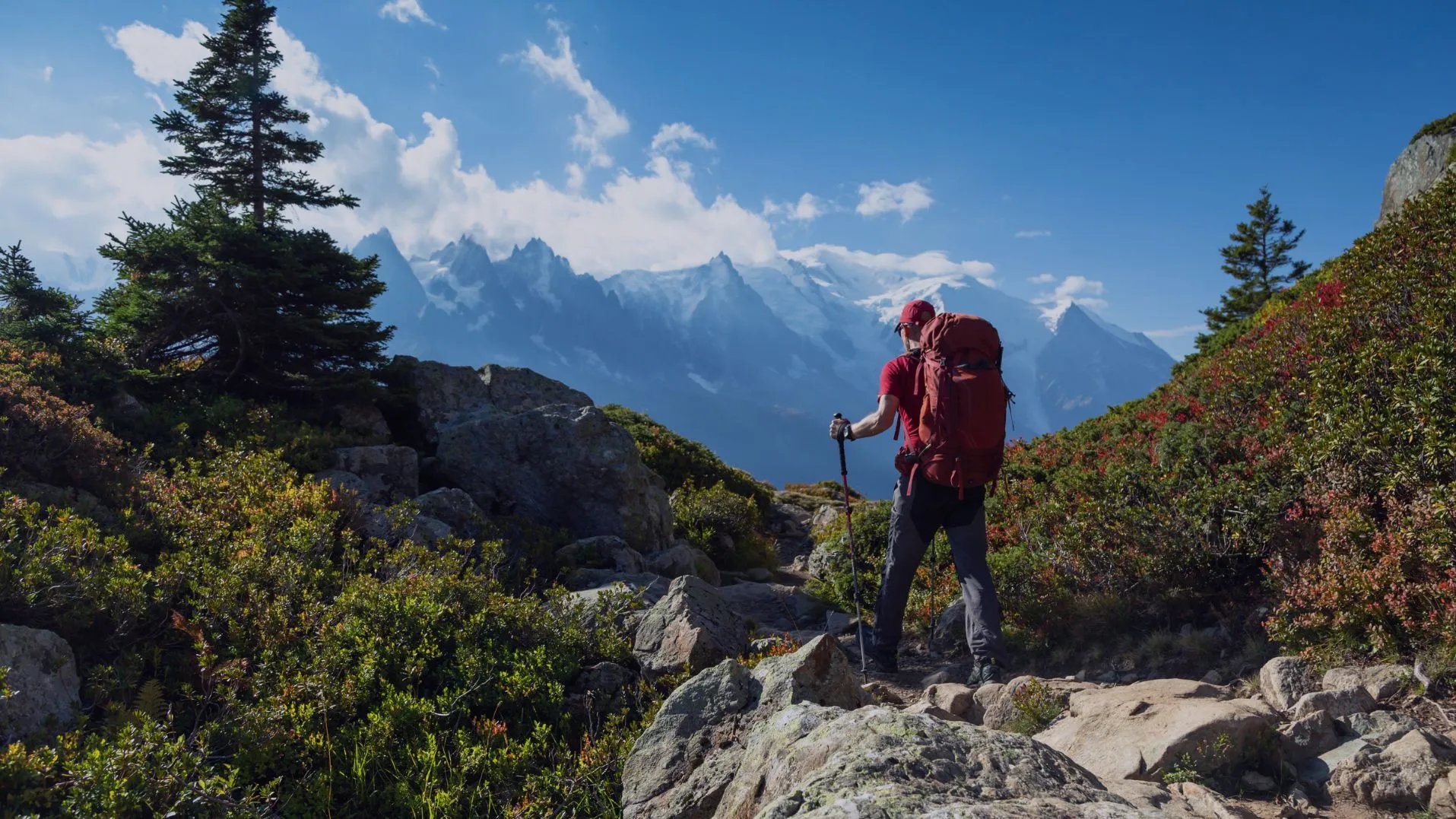 Wanderer mit großem roten Rucksack in felsiger Landschaft und atemberaubender Aussicht